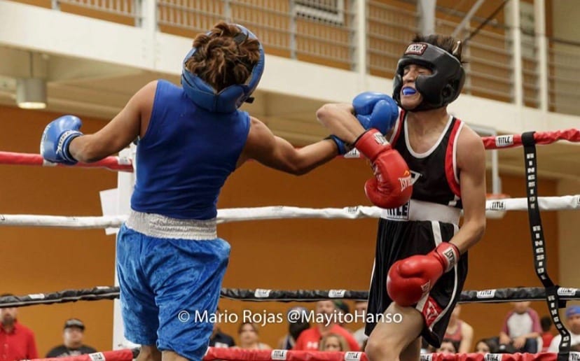 Senior, Kevin Mendoza strikes his opponent in the face during a boxing match.