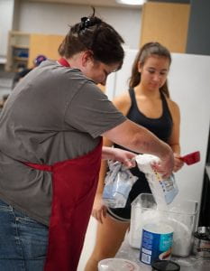 Mrs. Bentley, food science teacher, adds more flour so students can bake