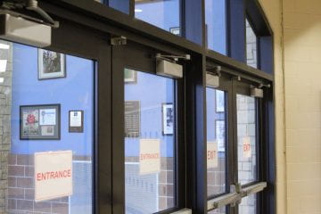 The doors leading to the B Wing and fine arts wing have red and white entrance and exit signs in the middle of the glass.