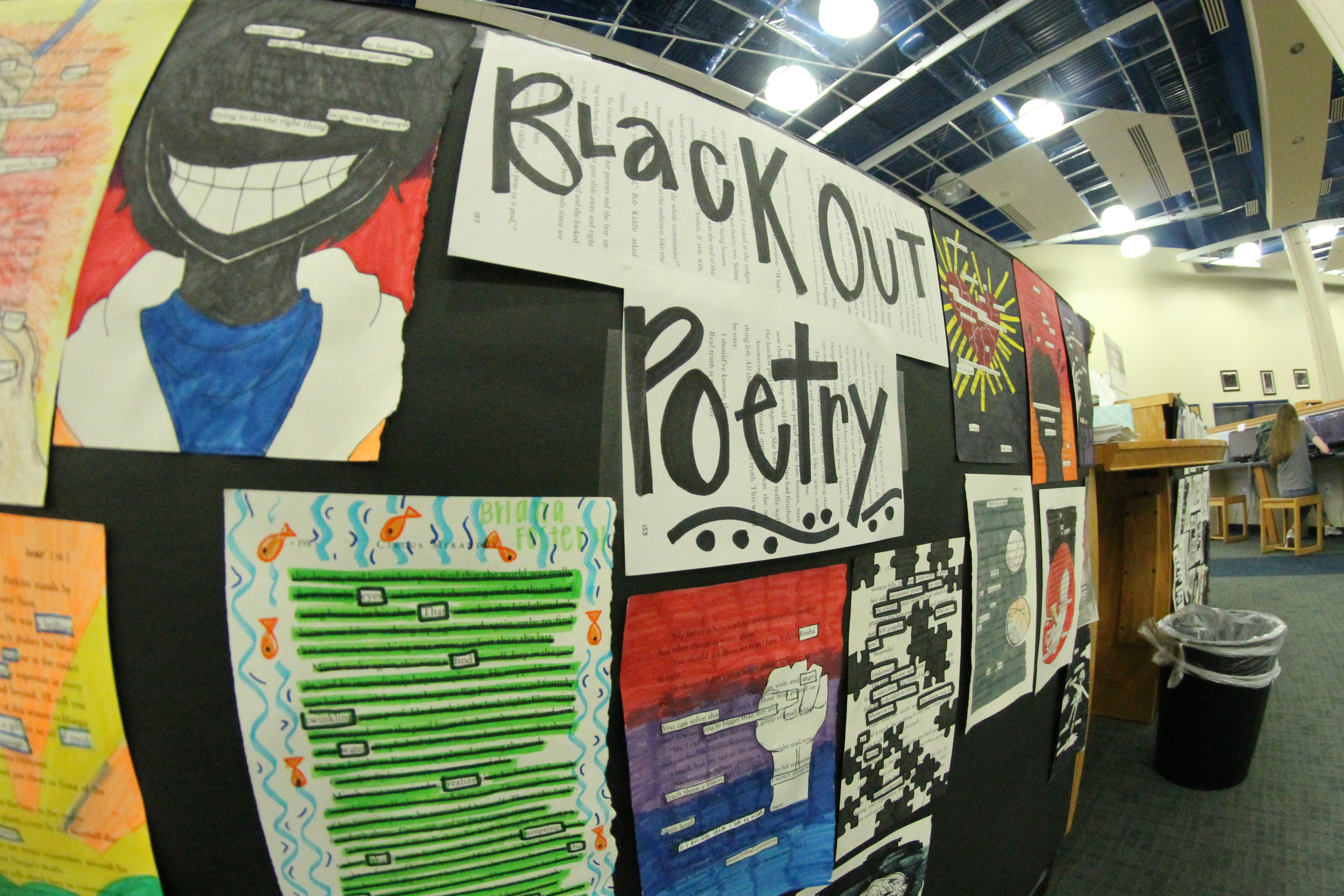 Colorful blackout poetry hangs on a black poster.