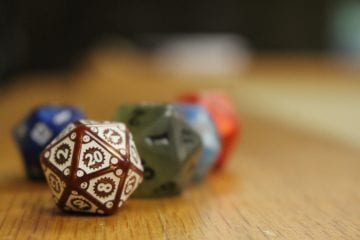 4 20 sided dice sit on a wooden shelf