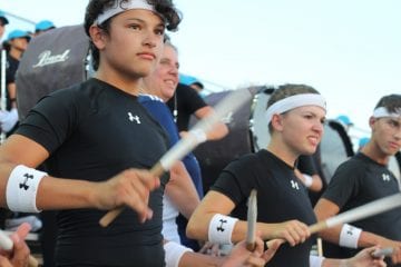 Band students play the drums during a football game