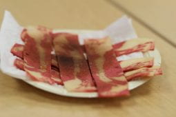 A plate with paper towels sits on a desk, serving strips of horrific vegan bacon.