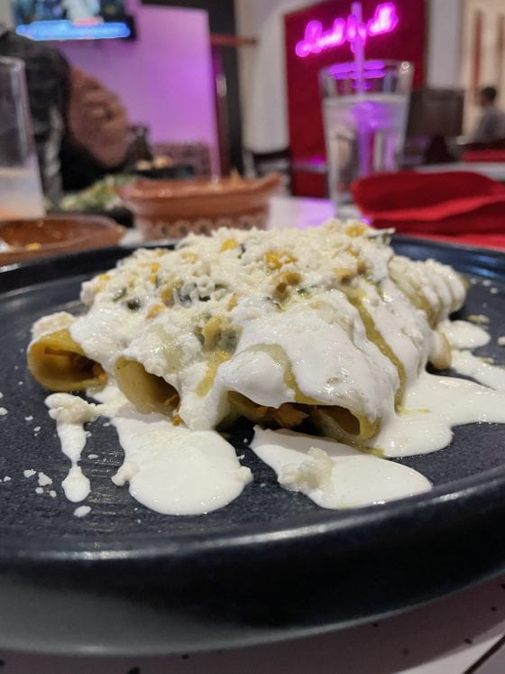Creamy chicken poblanas enchiladas, topped with sour cream and queso fresco.