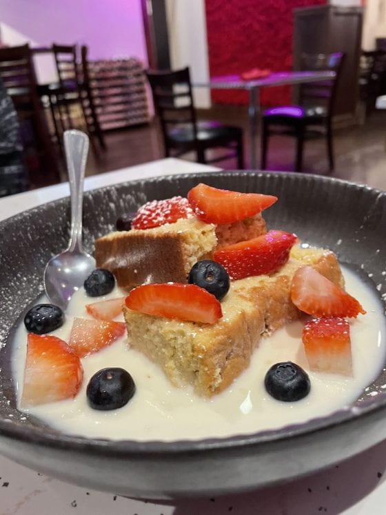Tres leches - vanilla cake soaked with whole milk, evaporated milk, and condensed milk. It is surrounded by strawberries and blueberries.