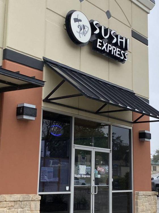 The outside of the Sushi Express restaurant, with an "open sign"