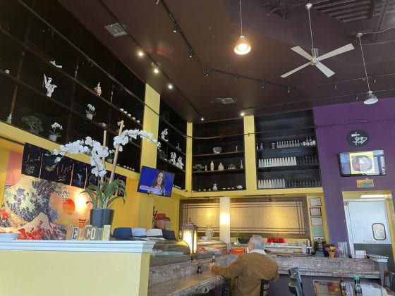 The interior of Sushi Express, with the sushi bar, tables, and decor
